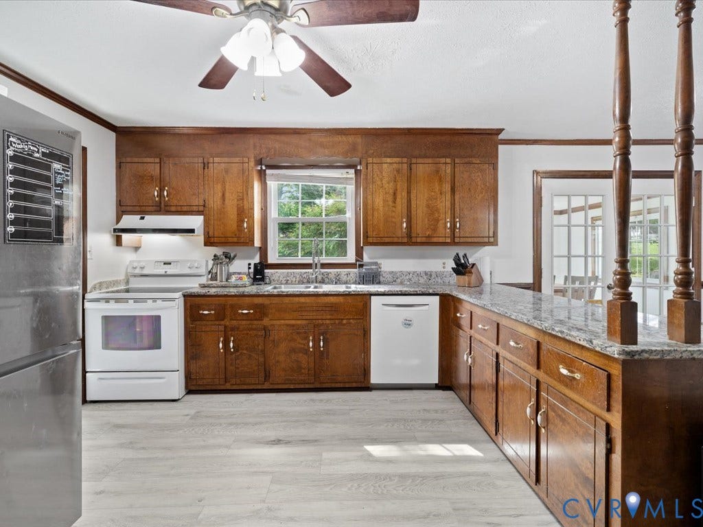 Kitchen featuring wood cabinetry, light-toned flooring, white appliances, and a ceiling fan