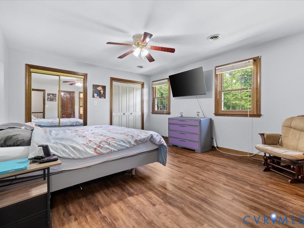 Wood-finish flooring, white walls, and a ceiling fan with integrated lighting