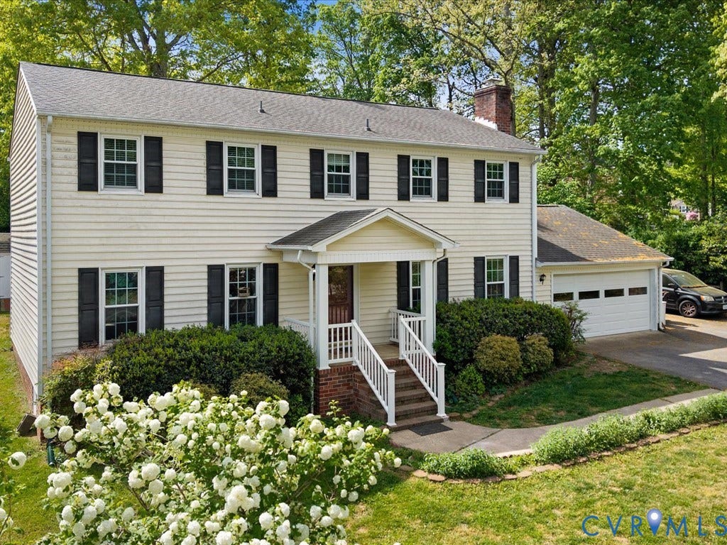 Two-story residence featuring siding exterior, an attached garage, and a covered front porch with white railings