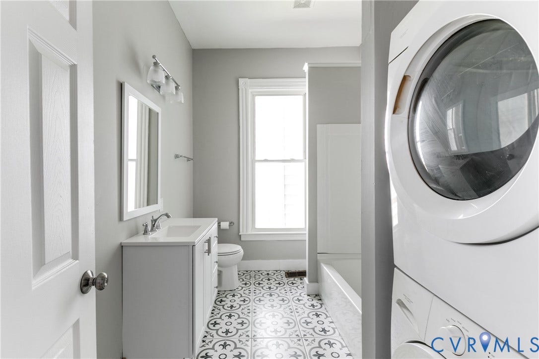 704 Chimborazo Boulevard, Chimborazo, Richmond, VA 23223 Bathroom featuring a white single-sink vanity, patterned tile flooring, a bathtub, and a stackable washer and dryer unit