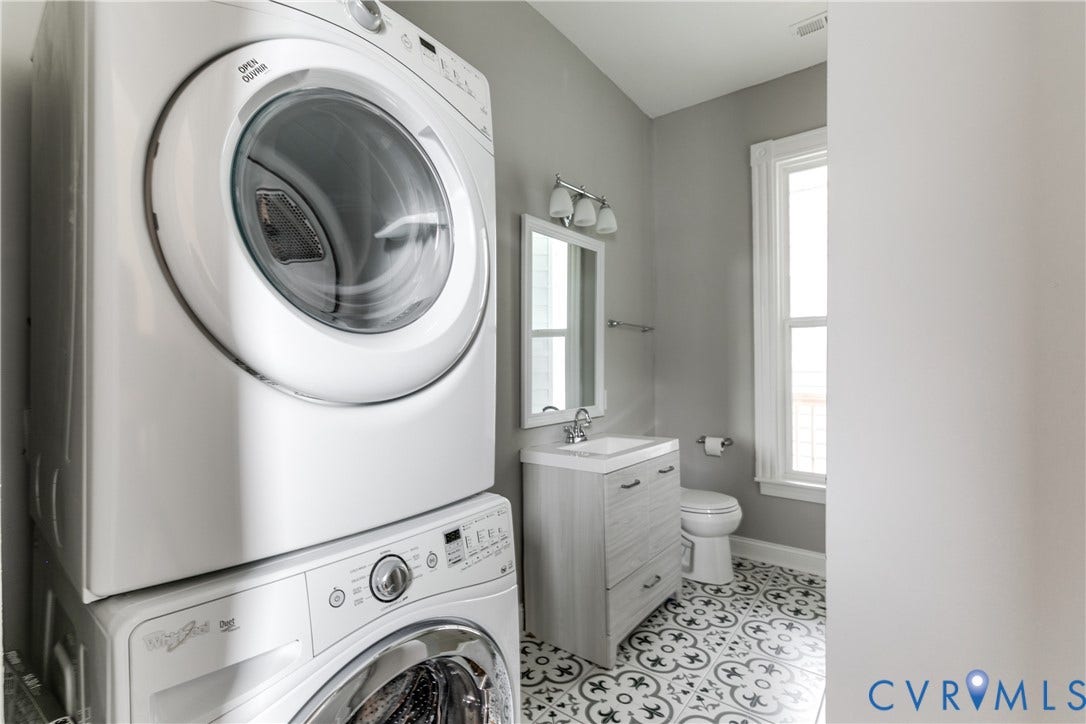 704 Chimborazo Boulevard, Chimborazo, Richmond, VA 23223 Full-size stacked laundry appliances, patterned floor tile, single vanity with integrated sink, chrome faucet, and wall-mounted mirror
