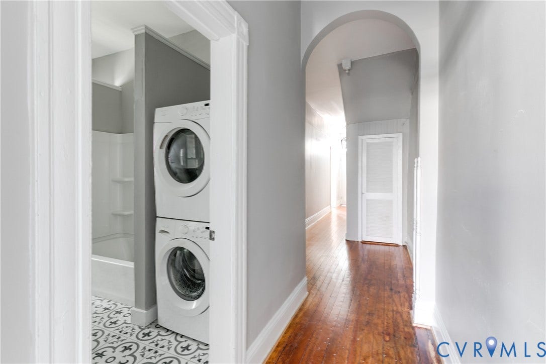704 Chimborazo Boulevard, Chimborazo, Richmond, VA 23223 Stacked laundry appliances, patterned floor tile, full shower/tub combination, wood-finish flooring, and an arched hallway opening