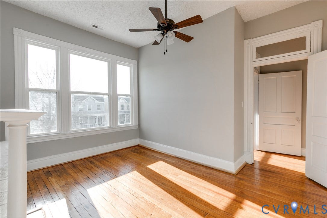 704 Chimborazo Boulevard, Chimborazo, Richmond, VA 23223 Hardwood flooring, multi-pane windows with detailed trim, architectural doorway with transom, and a ceiling fan