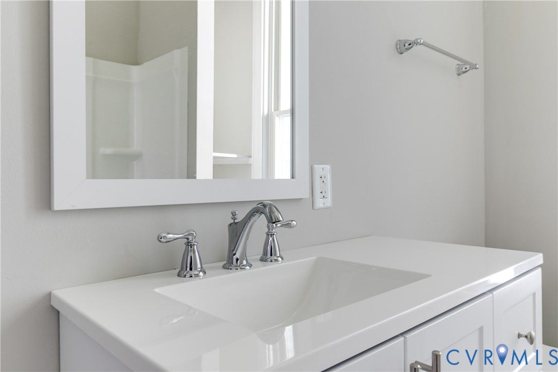 704 Chimborazo Boulevard, Chimborazo, Richmond, VA 23223 White vanity with a polished chrome faucet, rectangular undermount sink, and a framed mirror