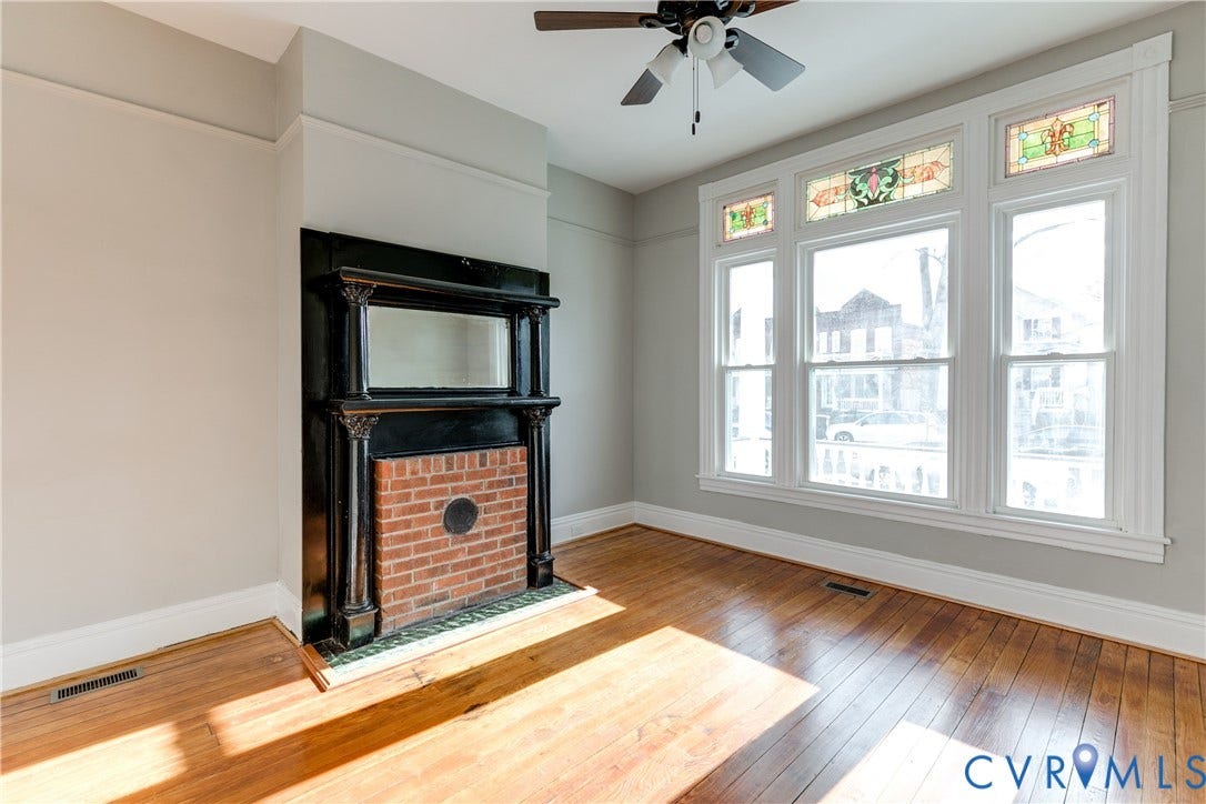 704 Chimborazo Boulevard, Chimborazo, Richmond, VA 23223 Hardwood flooring, decorative fireplace with brick surround, built-in mirror, stained-glass transom windows, and a ceiling fan