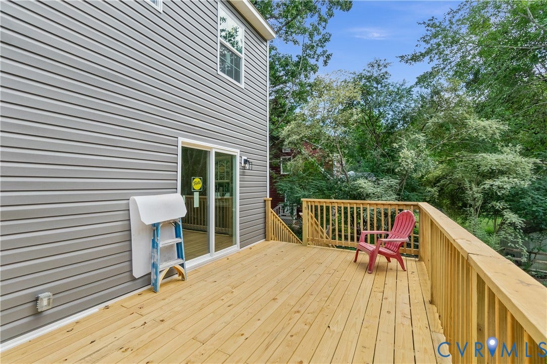 Expansive wood deck with natural wood railing, grey horizontal siding, and a sliding glass door