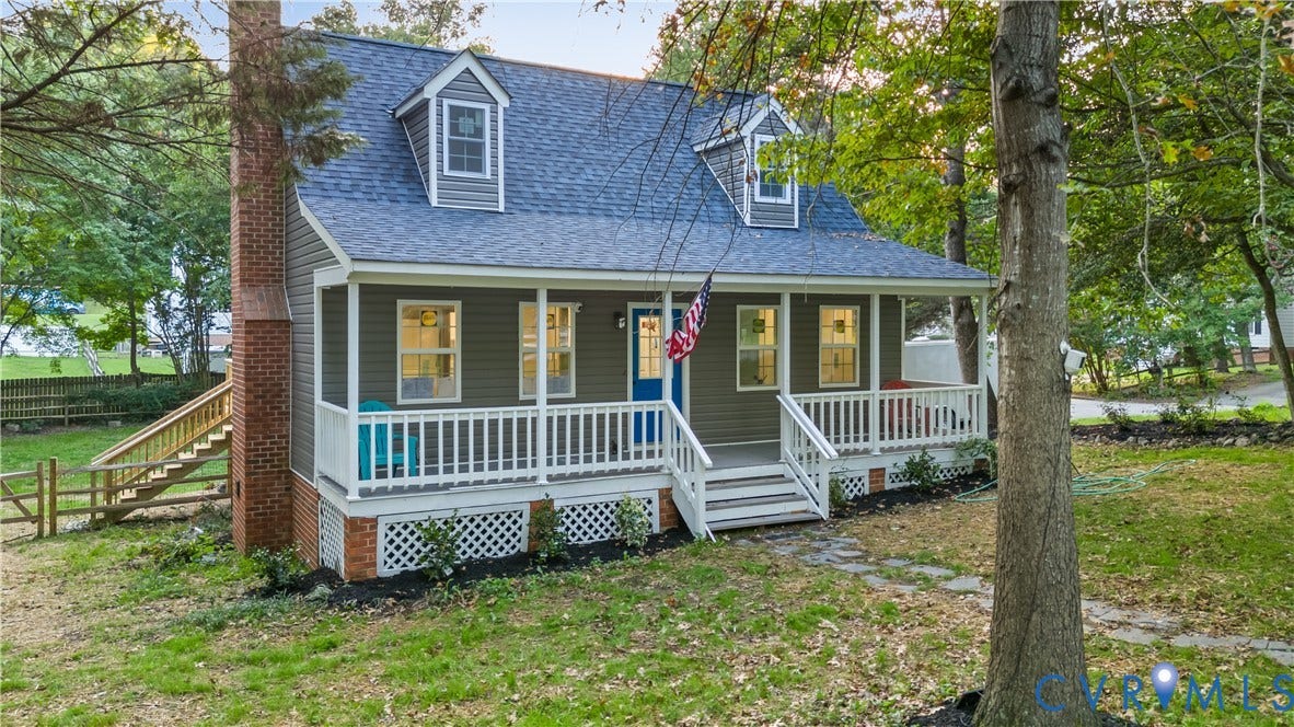 Siding exterior with a covered front porch, dormer windows, and a brick chimney