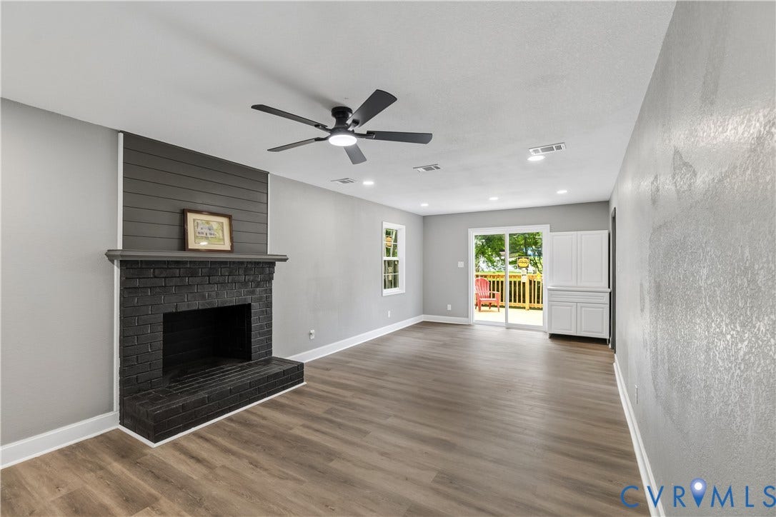 Contemporary interior with wood-finish flooring, a black brick fireplace with a shiplap accent wall, a ceiling fan, and recessed lighting