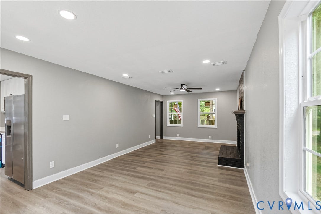 Recessed lighting, wood-finish flooring, ceiling fan, dark brick fireplace, and stainless steel refrigerator