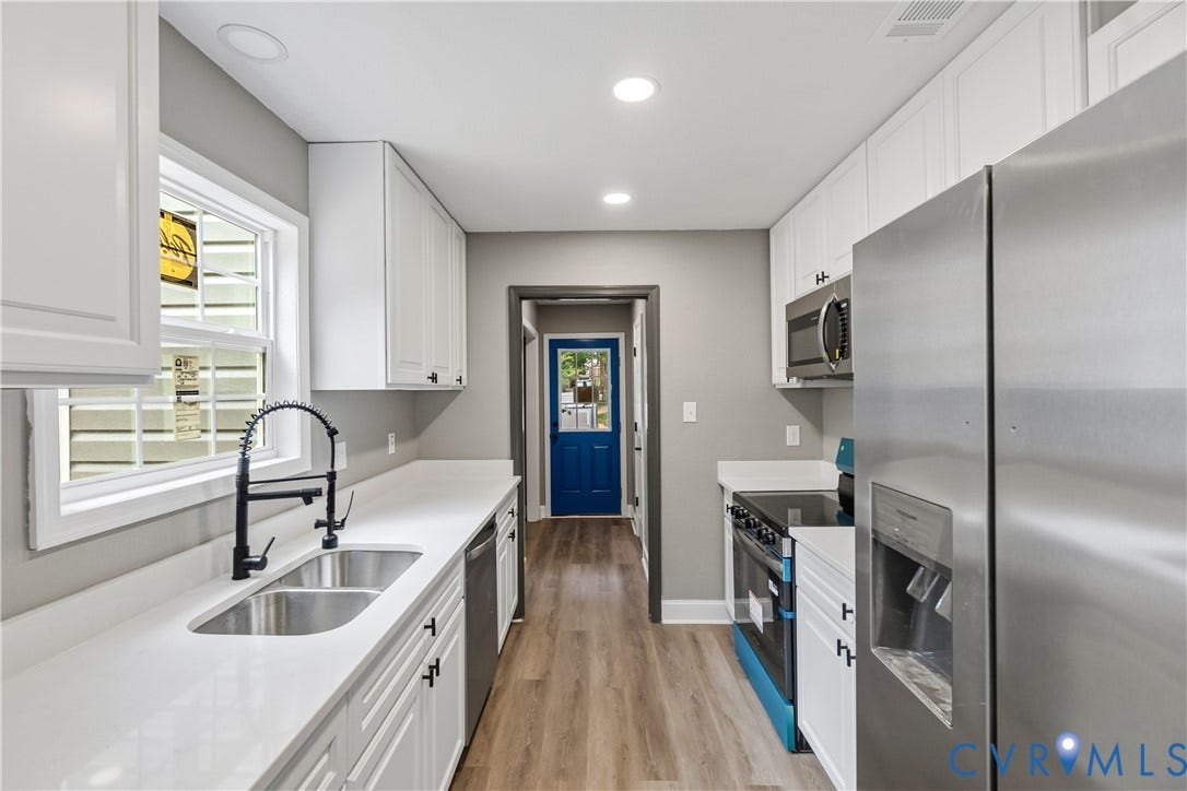 Galley kitchen featuring white cabinetry, light-toned countertops, wood-finish flooring, recessed lighting, and stainless steel appliances
