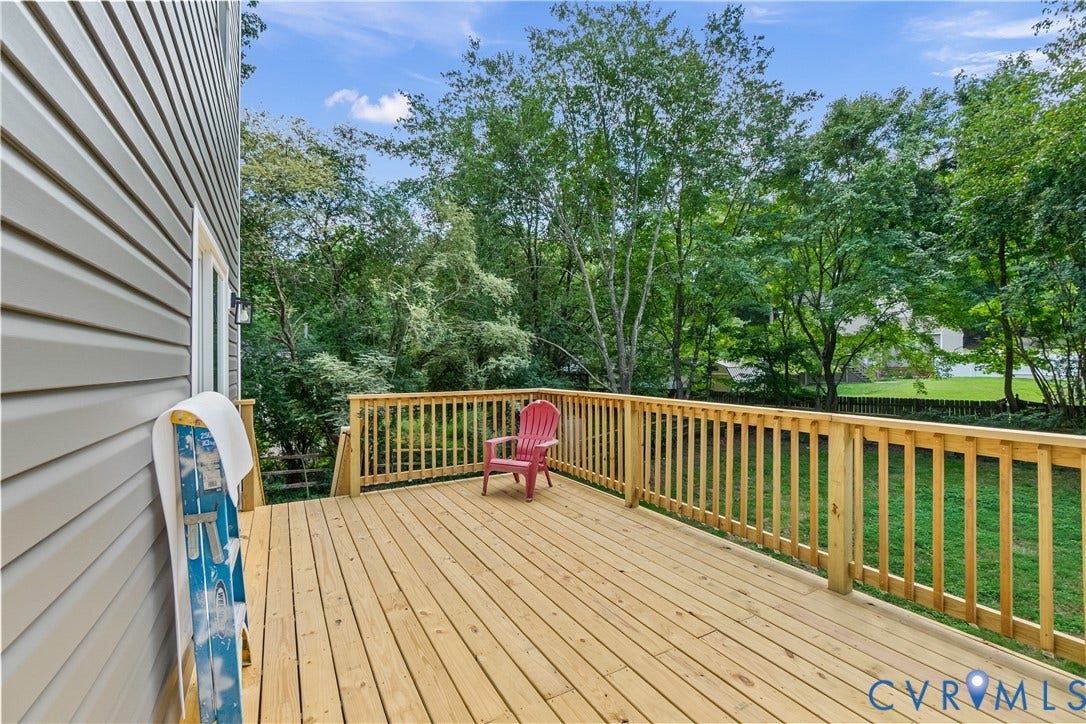 Expansive wooden deck with natural wood railing overlooking a grassy yard with mature trees