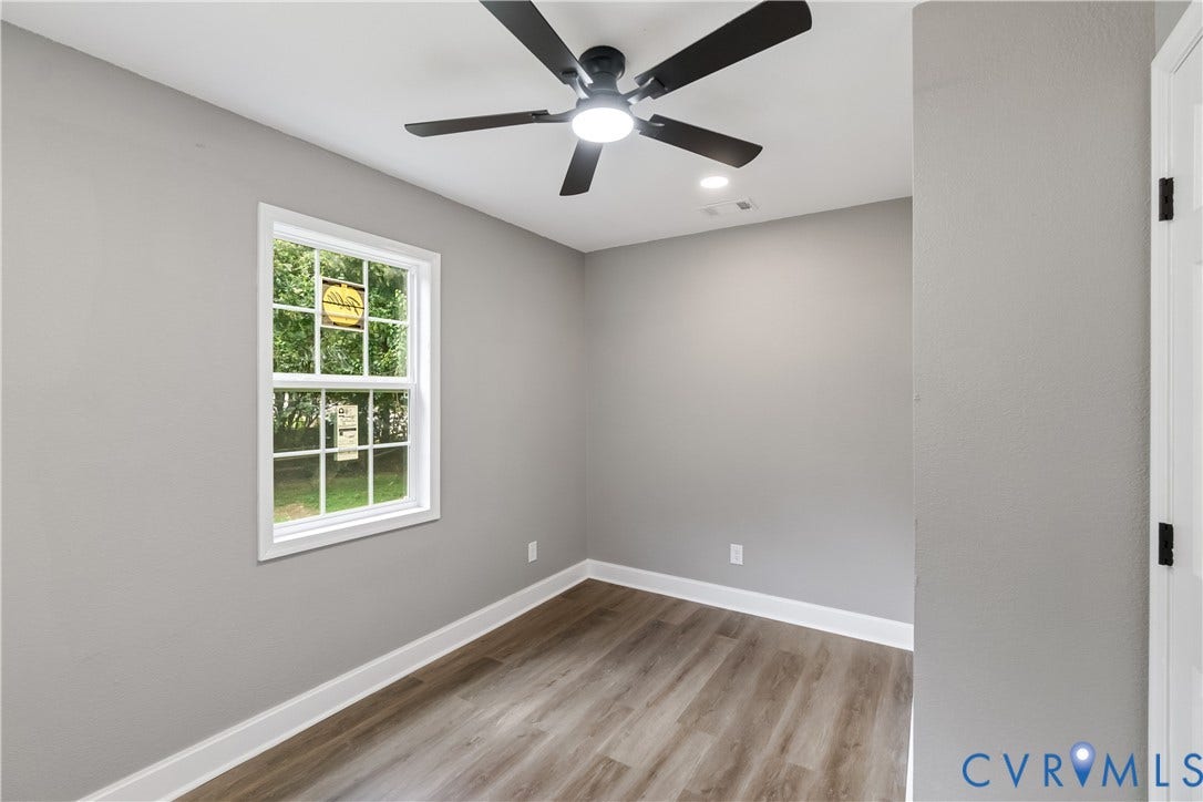 Light gray walls with white trim, wood-finish flooring, and a ceiling fan with integrated lighting