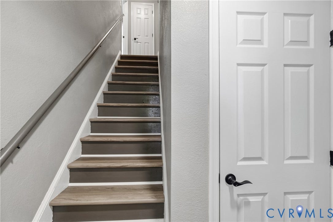 Staircase featuring wood-finish treads, painted risers, and a metal handrail