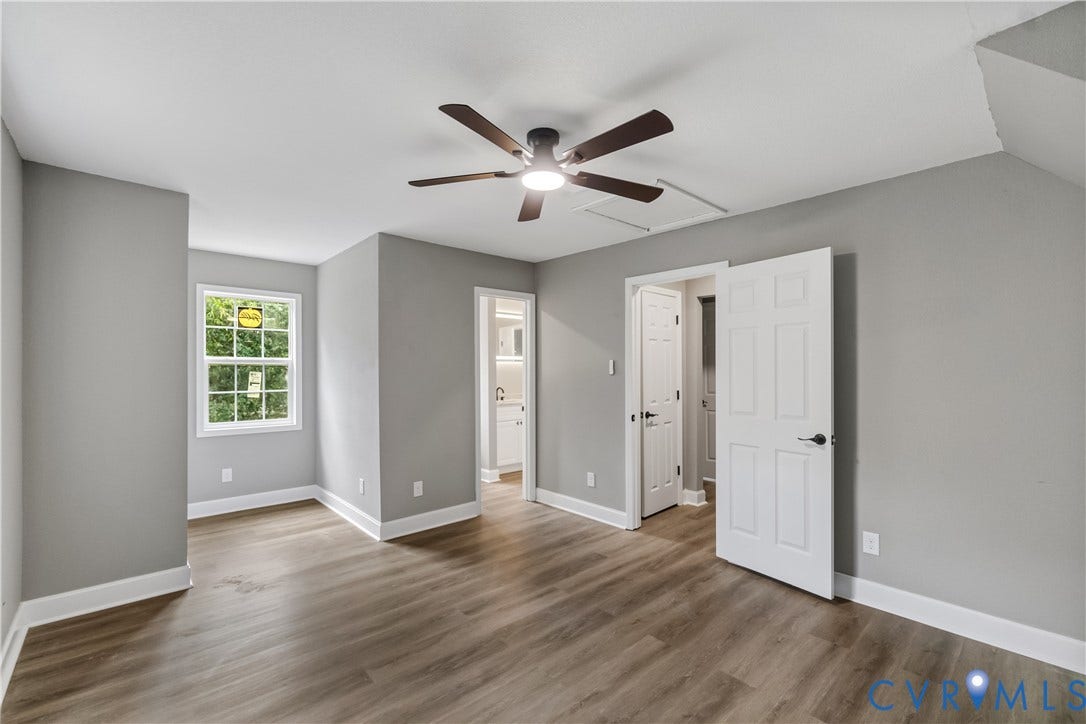 Spacious room featuring wood-finish flooring, a ceiling fan, and a double-pane window