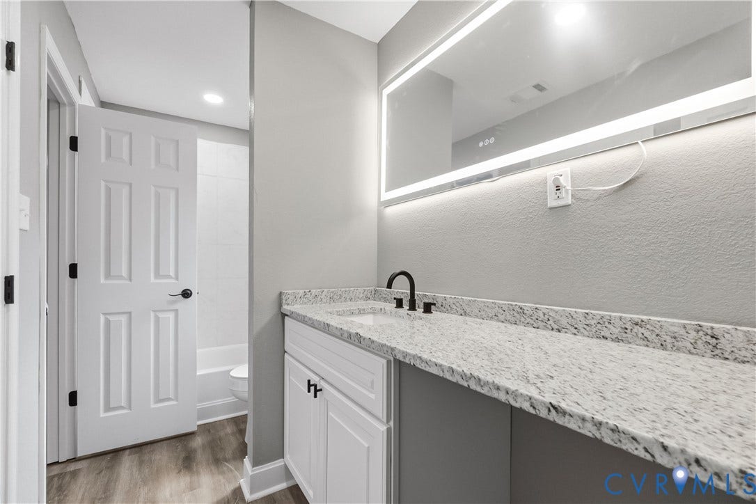 Extended vanity with a speckled countertop and a matte black faucet