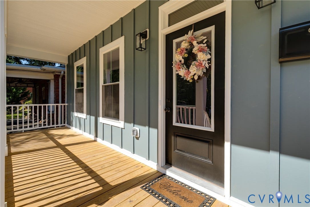 Covered front porch featuring wood-finish flooring, white railing, and board and batten siding