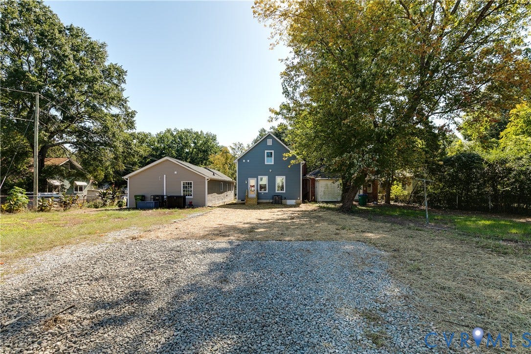 Gravel parking area leading to a blue siding residence with white trim and a gabled roof