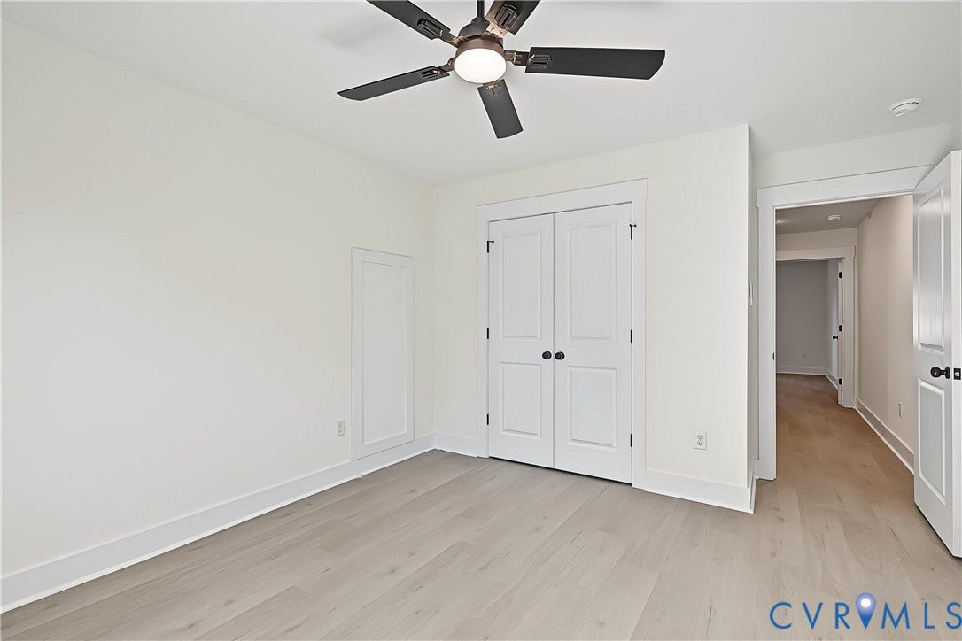 Wood-finish flooring, white paneled doors, ceiling fan with light fixture, and neutral wall tones