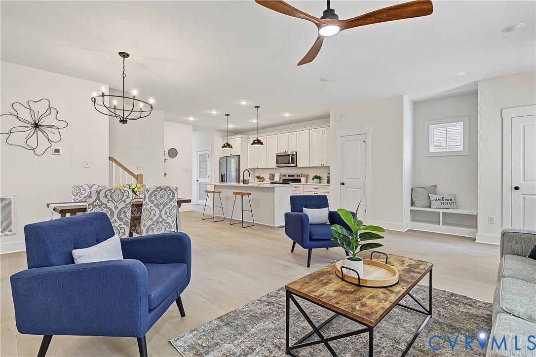 Open-concept living area with wood-finish flooring, recessed lighting, kitchen island with pendant lighting, and built-in entry bench