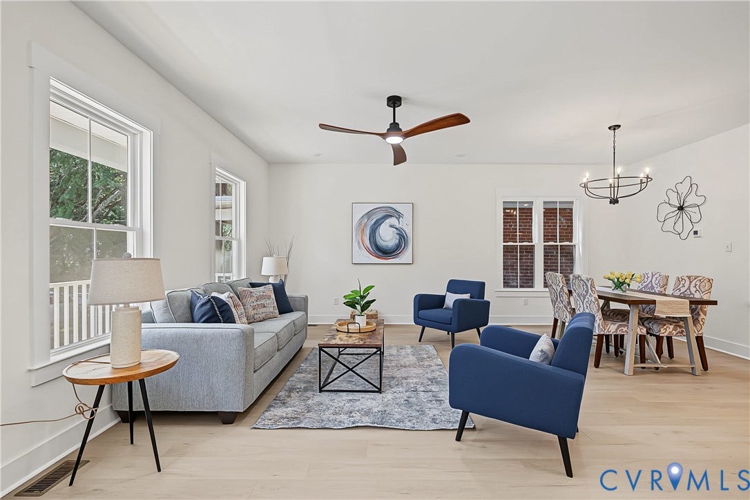 Open-concept living area featuring light wood-finish flooring, white walls, and a modern ceiling fan