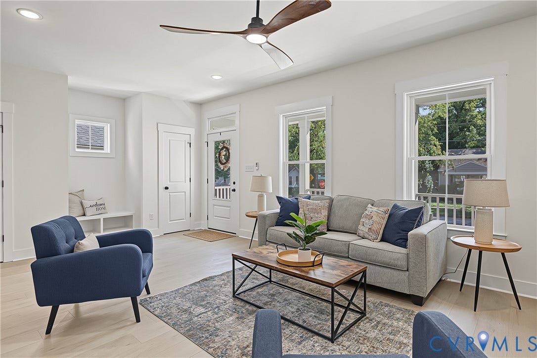 Spacious living area featuring light wood-finish flooring, a modern ceiling fan, recessed lighting, and ample natural light through multiple windows