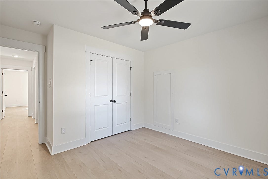 Wood-finish flooring throughout, white interior walls, ceiling fan with integrated lighting, and white bi-fold closet doors with dark hardware