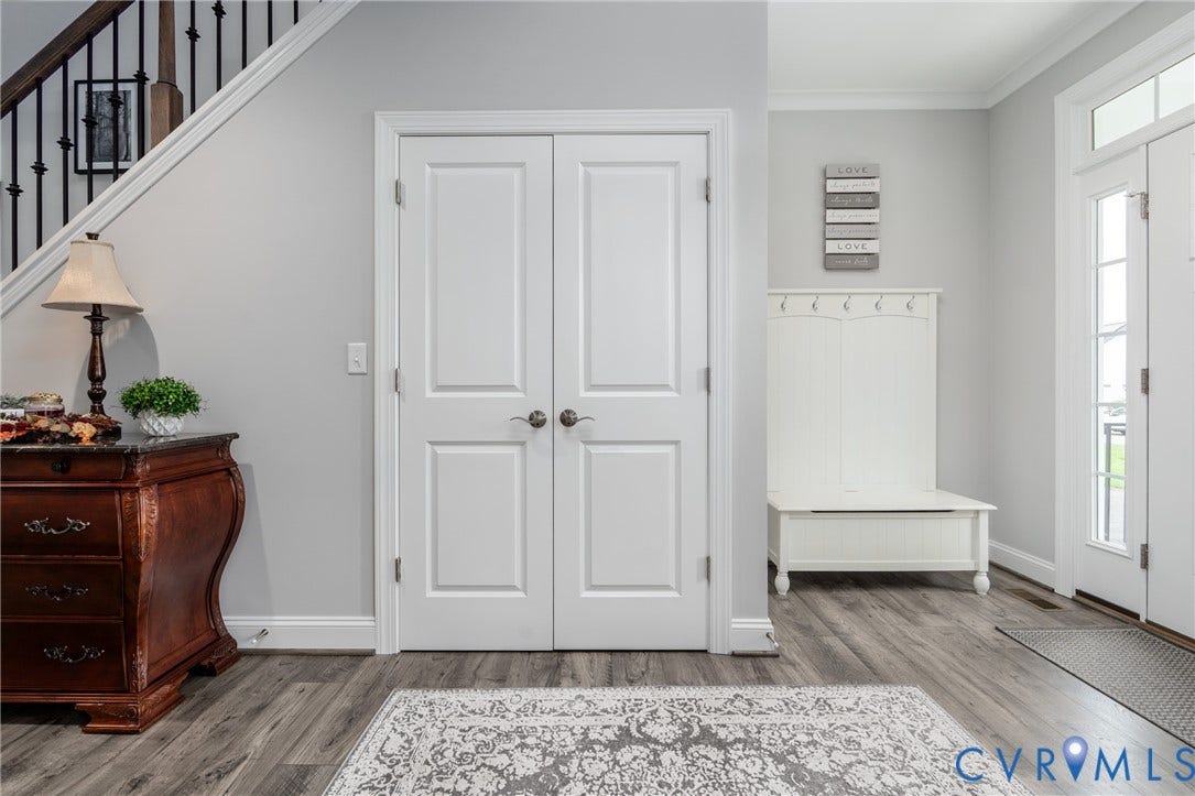 12303 Beech Hall Circle, Manakin Sabot, VA 23103 Wood-finish flooring throughout, white two-panel double doors, transom window above the entry door, and a staircase with dark metal balusters