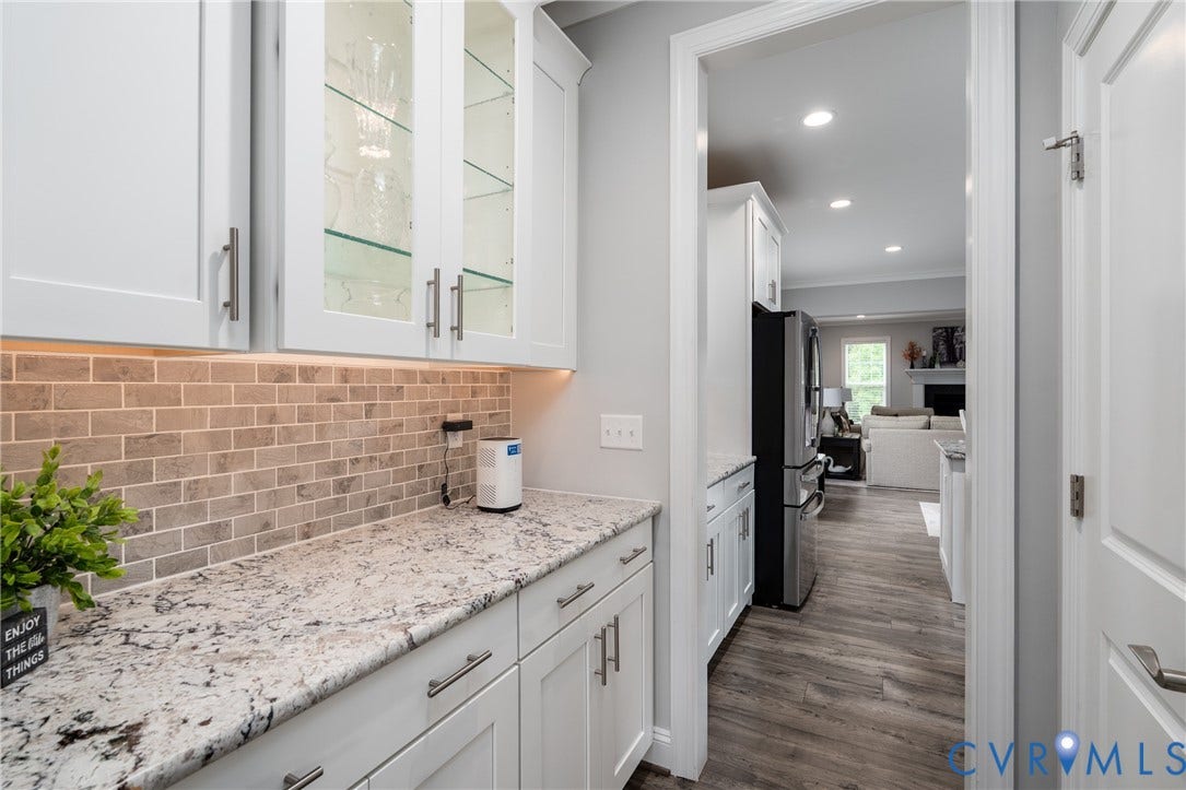 12303 Beech Hall Circle, Manakin Sabot, VA 23103 White cabinetry with glass-front uppers, light-toned stone countertop, subway tile backsplash, and wood-finish flooring