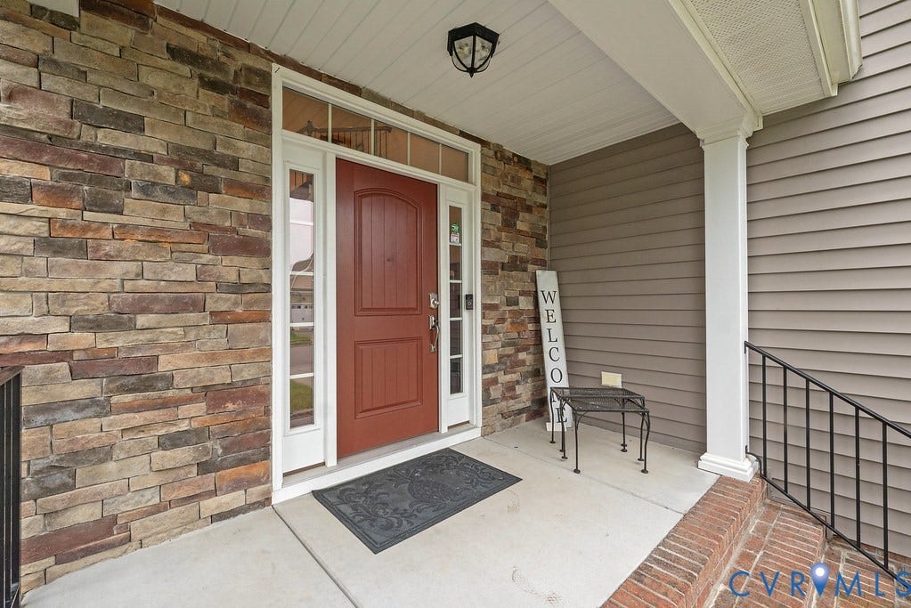 6301 Broad Sky Circle, Quiet, Mechanicsville, VA 23111 Covered front porch featuring a paneled entry door with sidelights and transom, stone veneer siding, and a white column
