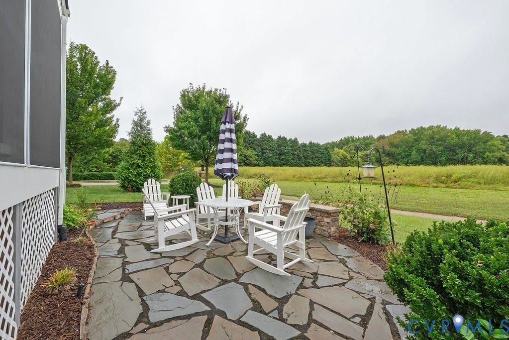 6301 Broad Sky Circle, Quiet, Mechanicsville, VA 23111 Expansive flagstone patio with a stone retaining wall, bordering manicured landscaping and a screened porch