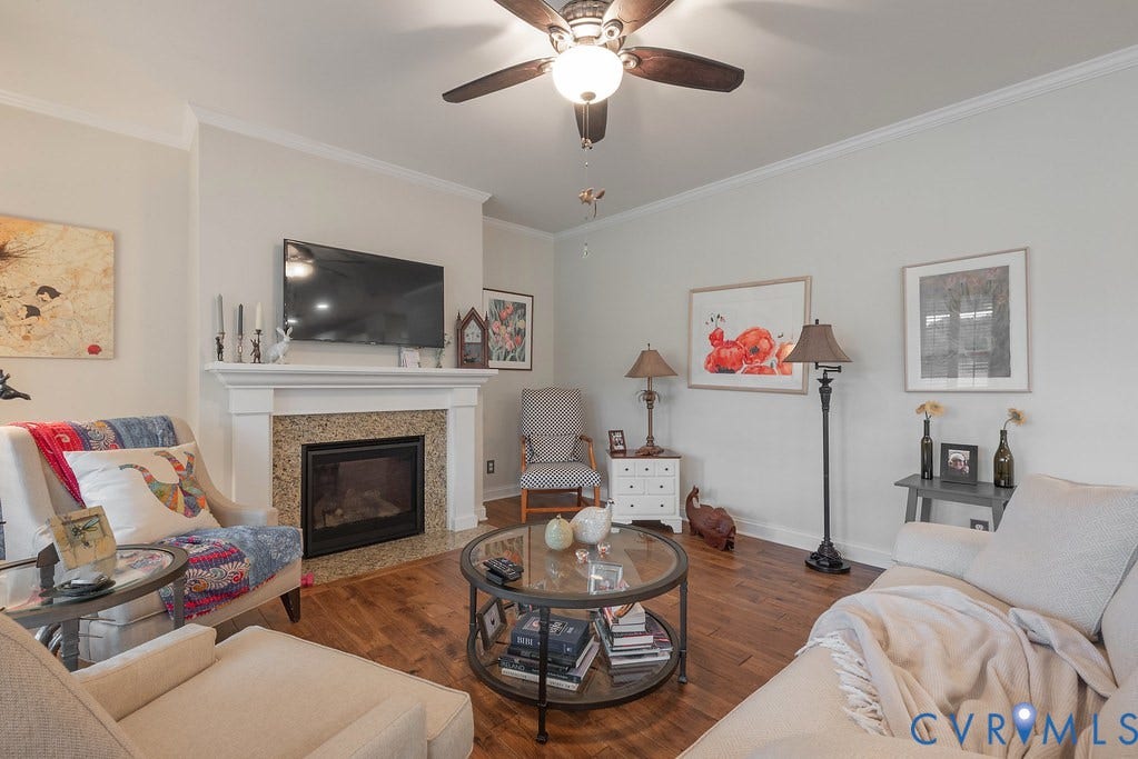 6301 Broad Sky Circle, Quiet, Mechanicsville, VA 23111 Living area featuring wood-finish flooring, a fireplace with a stone surround and white mantel, crown molding, and a ceiling fan with integrated lighting
