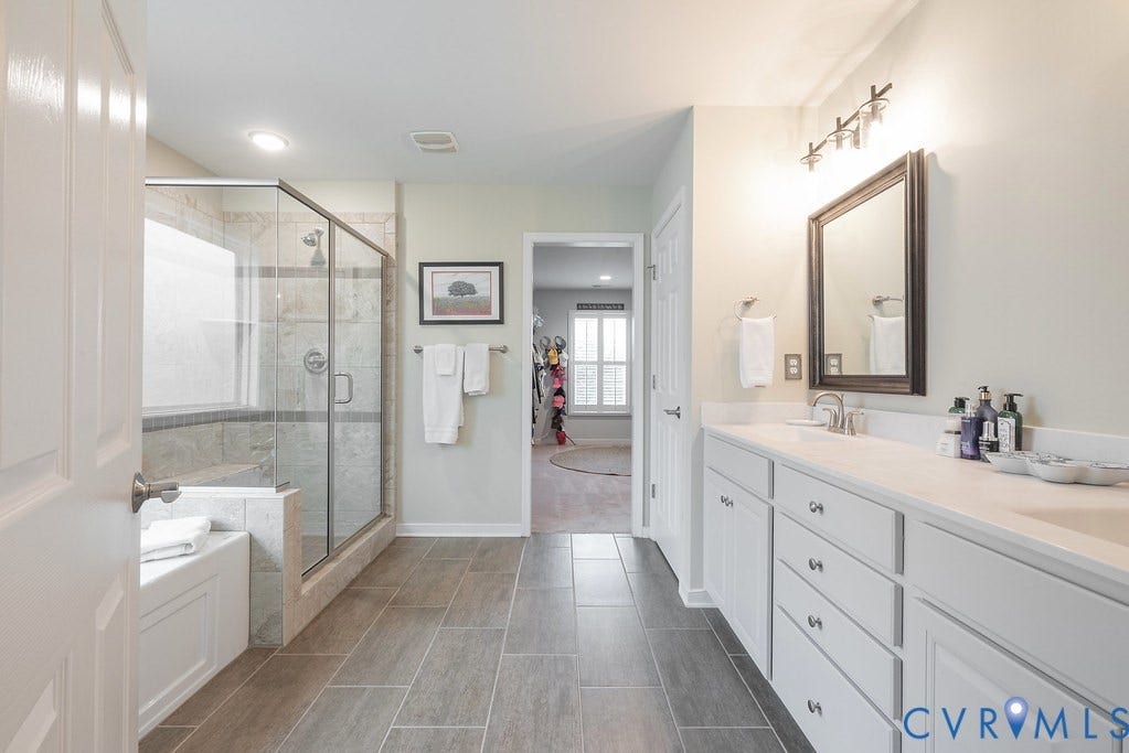 6301 Broad Sky Circle, Quiet, Mechanicsville, VA 23111 Double vanity with white cabinetry, a glass-enclosed shower, a built-in tub, and tile flooring