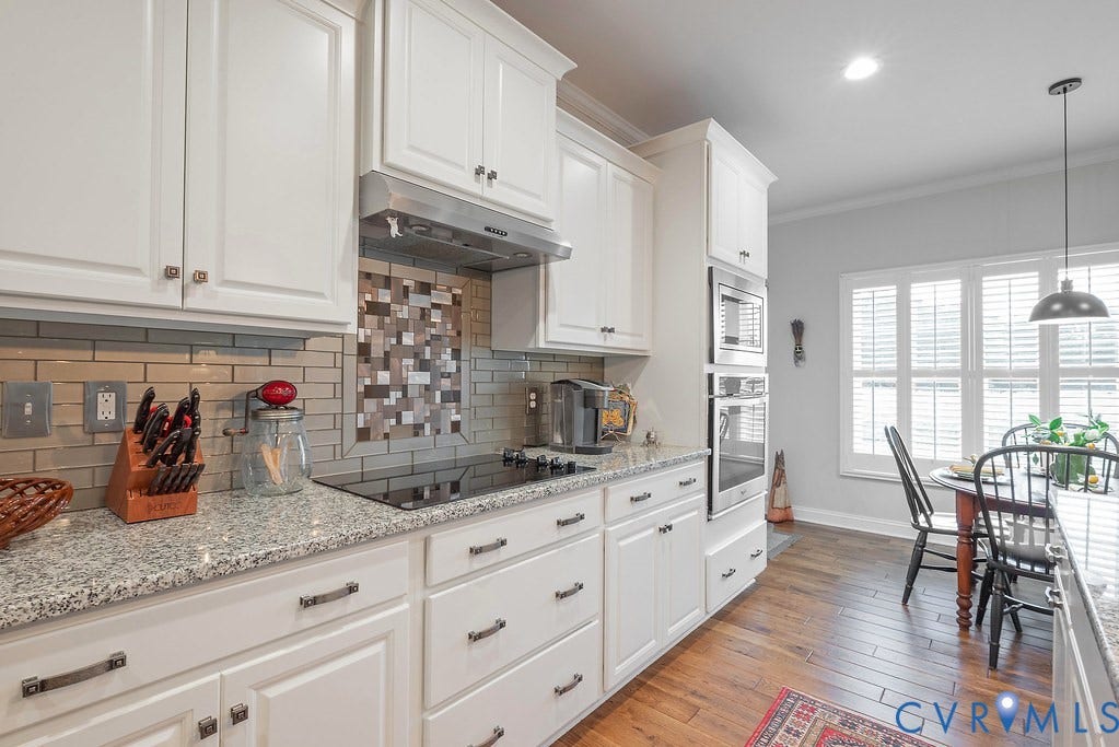 6301 Broad Sky Circle, Quiet, Mechanicsville, VA 23111 White cabinetry with dark hardware, granite countertops, tile backsplash, built-in stainless steel appliances, and wood-finish flooring