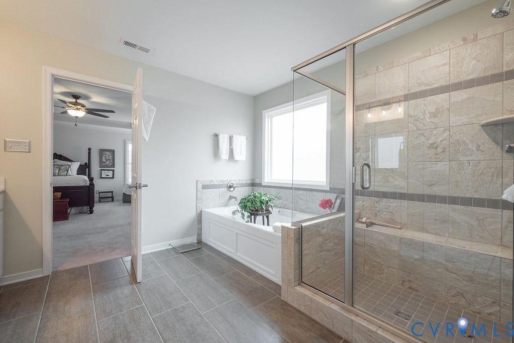 6301 Broad Sky Circle, Quiet, Mechanicsville, VA 23111 Spacious bathroom featuring large format tile flooring, a built-in soaking tub, and a glass-enclosed shower with tile surround