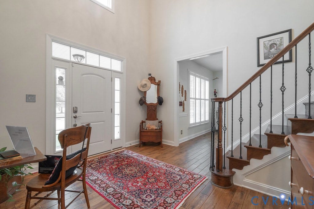 6301 Broad Sky Circle, Quiet, Mechanicsville, VA 23111 Two-story foyer featuring wood-finish flooring, a white paneled entry door with sidelights and transom, and a staircase with dark wood handrails and wrought iron spindles