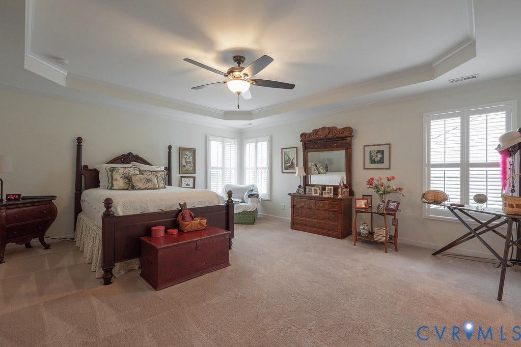 6301 Broad Sky Circle, Quiet, Mechanicsville, VA 23111 Tray ceiling with crown molding, ceiling fan with integrated lighting, multiple windows with plantation shutters, light-colored carpeting, and neutral wall paint