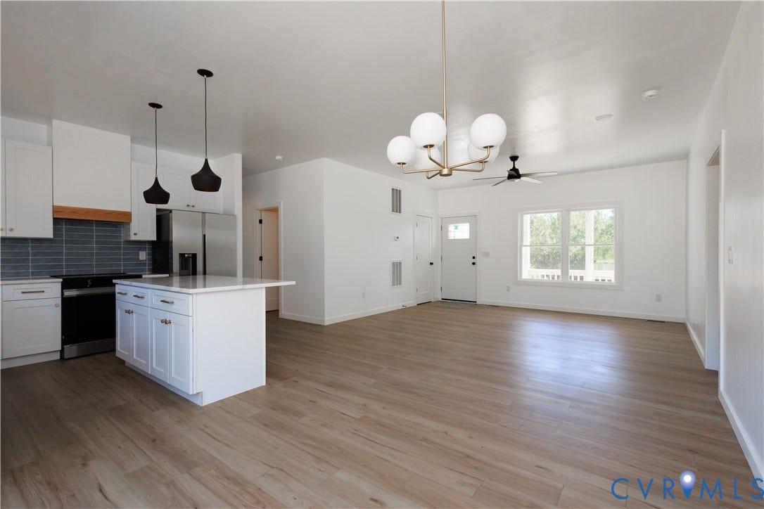 4805 Indian Creek Road, Mineral, VA 23117 Open-concept living area featuring wood-finish flooring, white cabinetry, a kitchen island, integrated stainless steel appliances, and a tiled backsplash