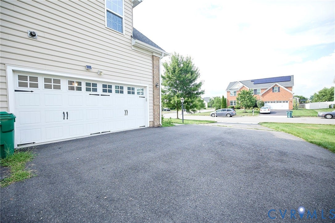 Attached two-car garage with white paneled doors and decorative hardware