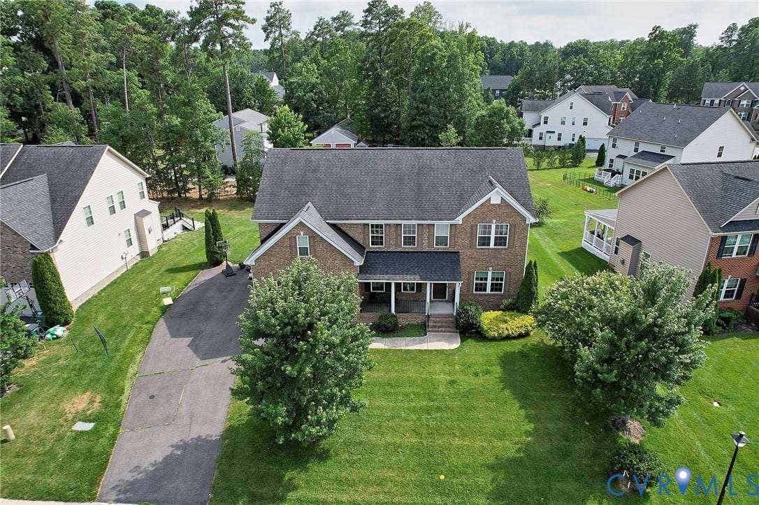 Two-story brick facade residence with a covered porch, a gabled roofline, and a paved driveway