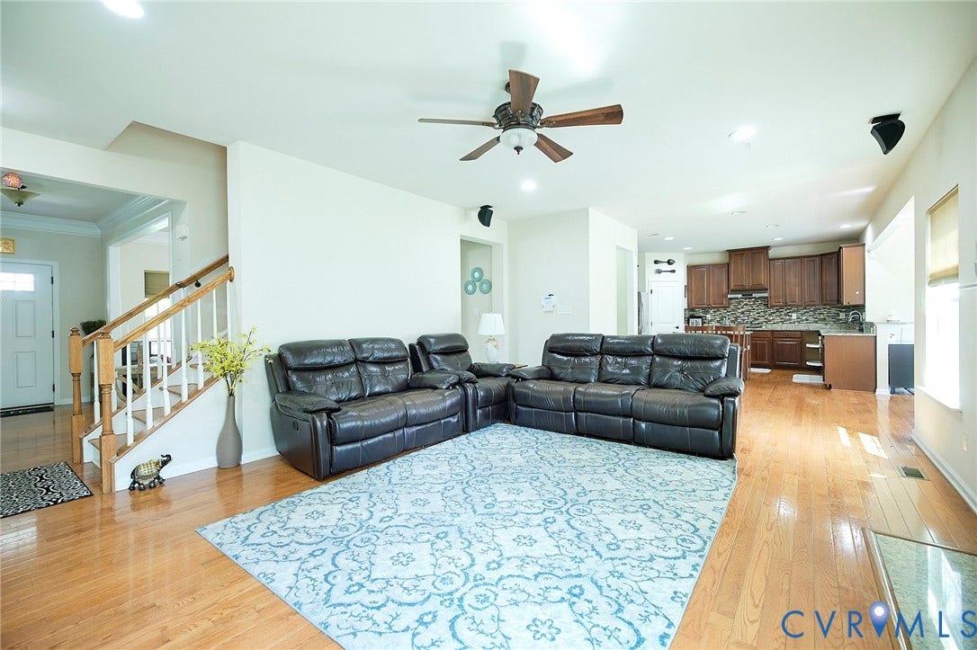 Open-concept living area with wood-finish flooring, a ceiling fan, and recessed lighting