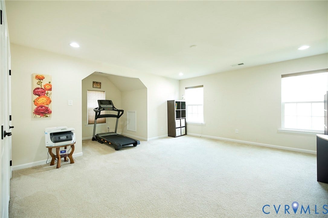 Spacious room featuring light-colored carpeting, multiple windows providing natural light, and recessed ceiling lighting