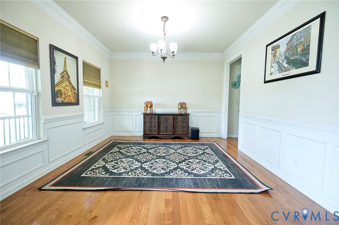 Hardwood flooring, elegant wainscoting, crown molding, double windows, and a chandelier lighting fixture