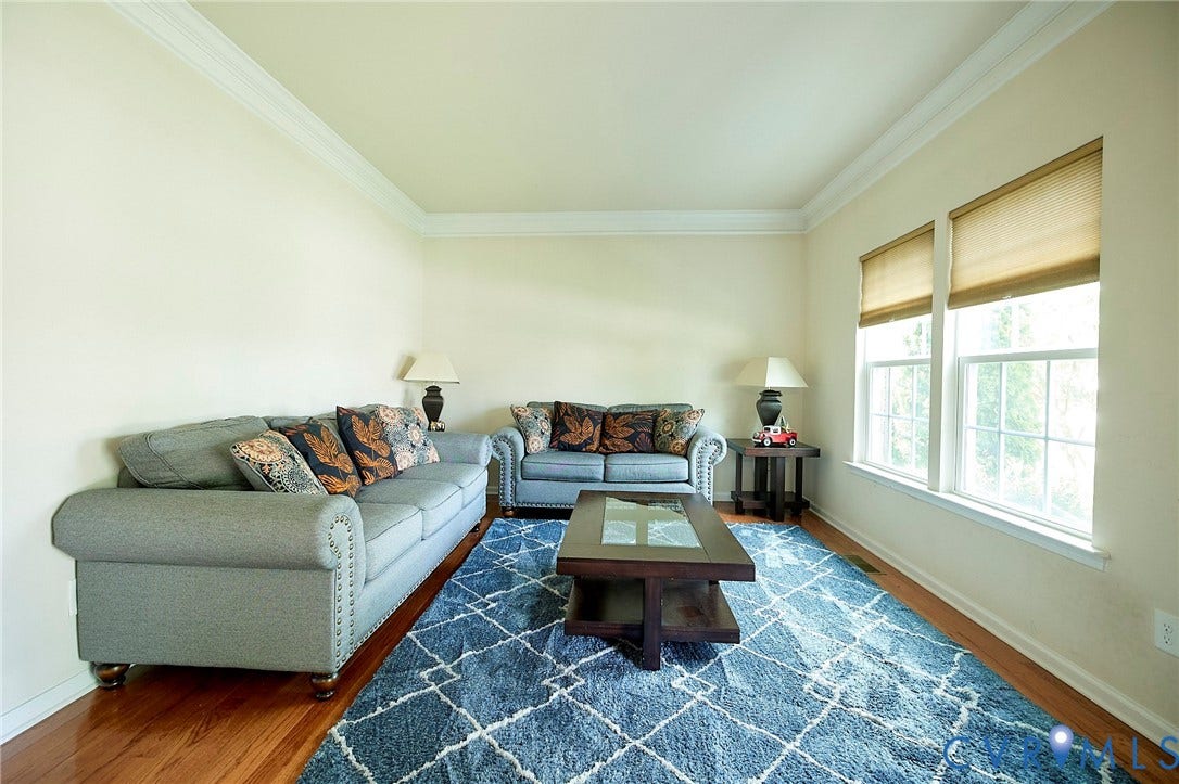 Wood-finish flooring, crown molding, and two windows with blinds