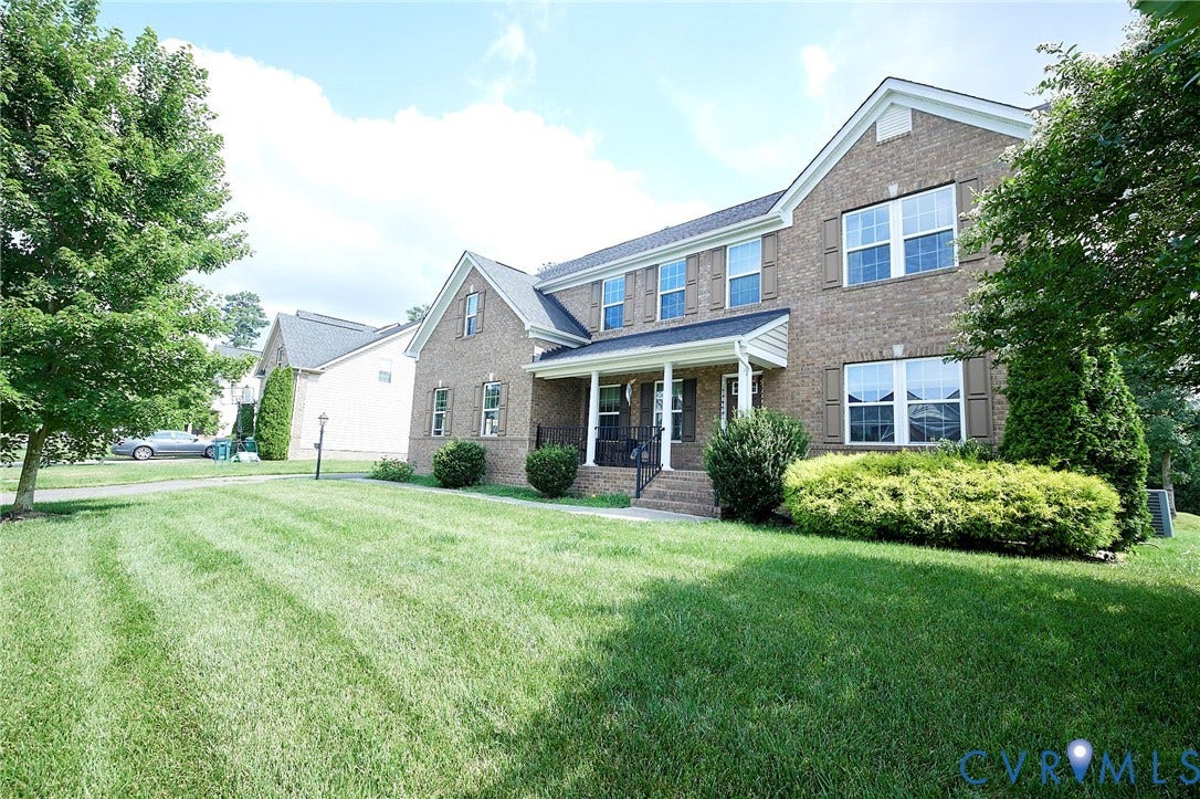 Brick exterior with multiple gables, covered front porch, double-hung windows with shutters, and established landscaping