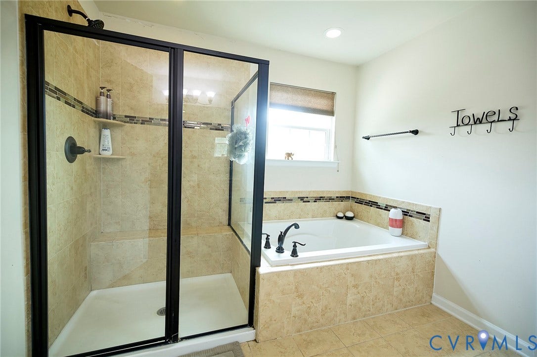 Tiled shower with glass enclosure and built-in bench, accompanied by an integrated soaking tub