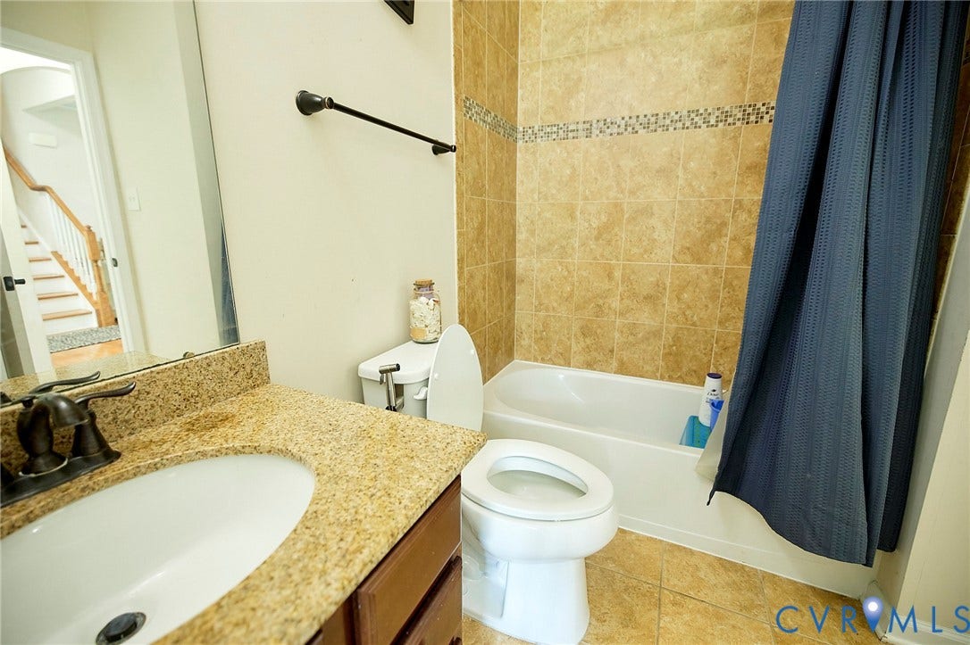 Bathroom featuring a single vanity with a built-in sink, a speckled countertop, and a dark bronze faucet