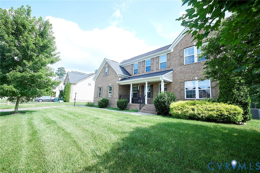 Brick exterior with multiple windows, covered front porch, and a well-maintained lawn