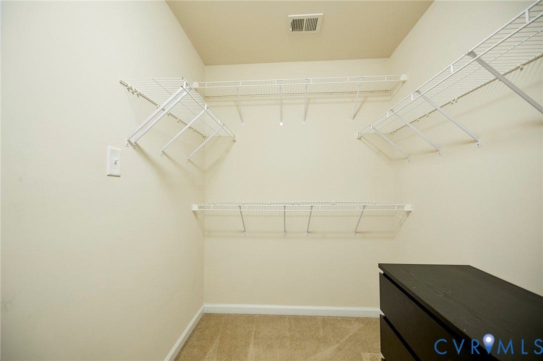 Carpeted interior with neutral wall tones and white wire shelving