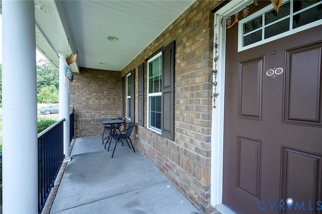 Brick exterior with white columns, a brown entry door, and dark shutters