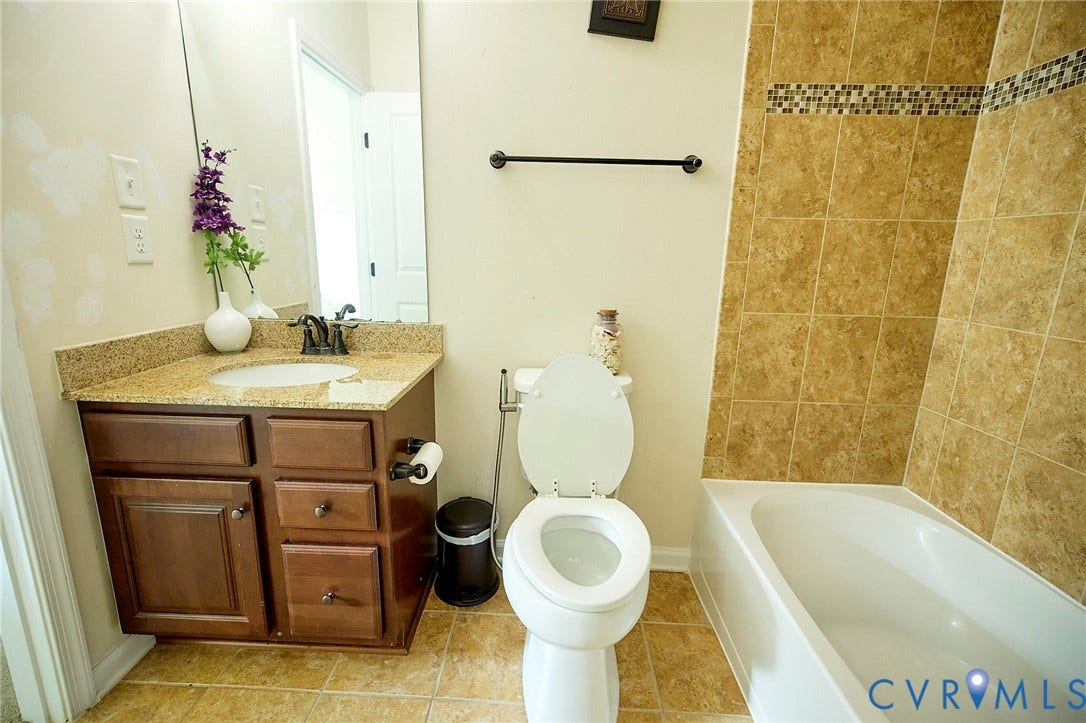 Wood-finish vanity with a granite-style countertop and undermount sink